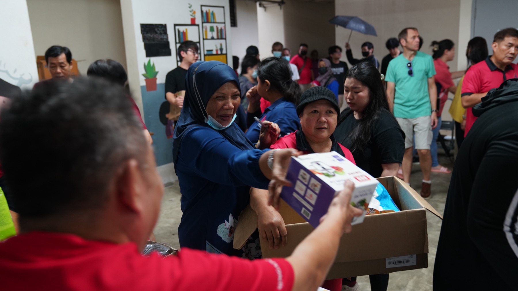 Volunteers handing grocery boxes to residents at a community distribution in Singapore